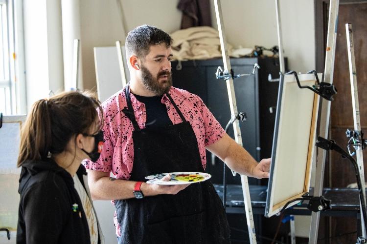 Eric works on a painting with consultation from a graduate assistant